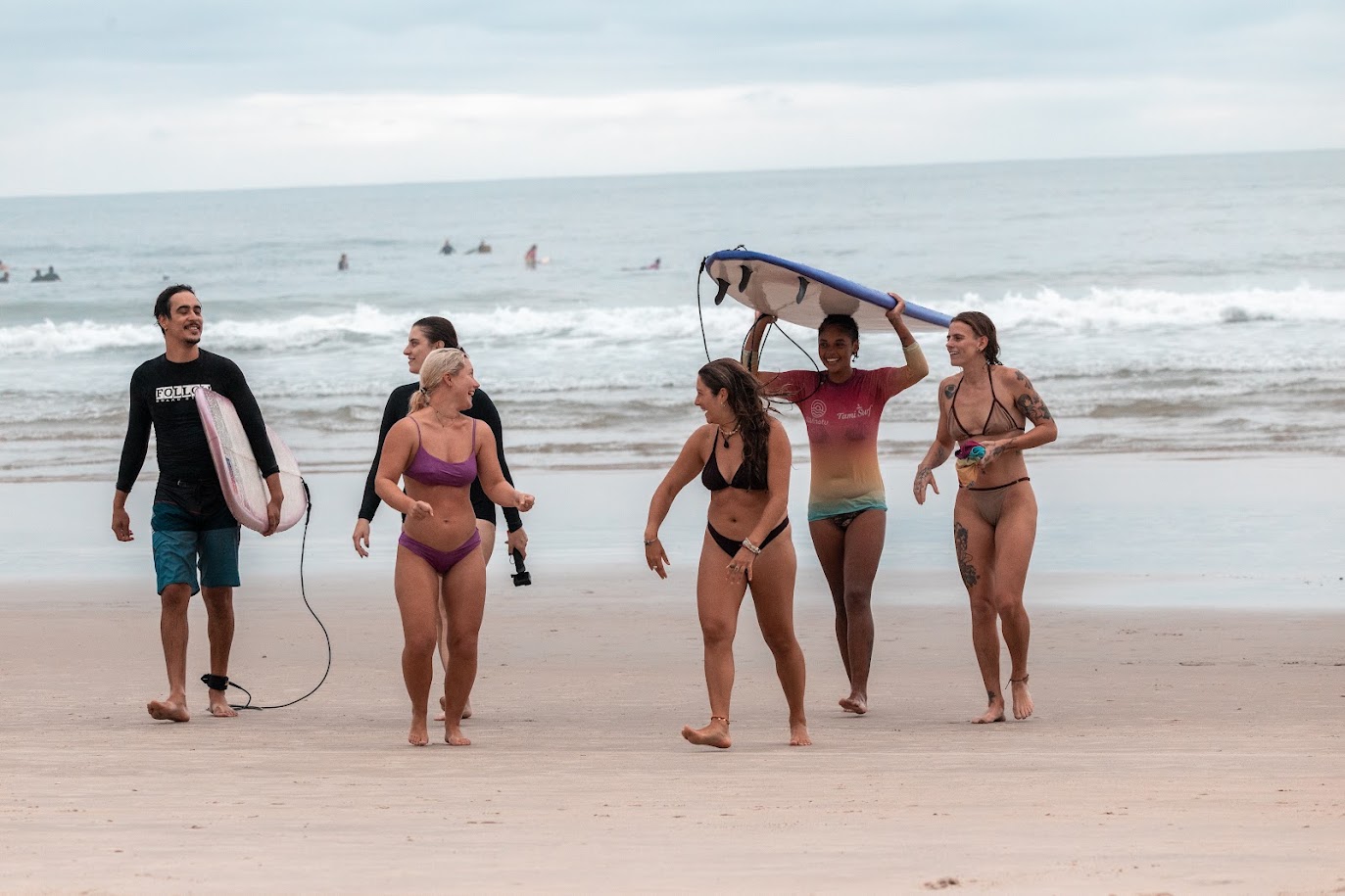 Galera caminhando na praia com as pranchas depois do surf