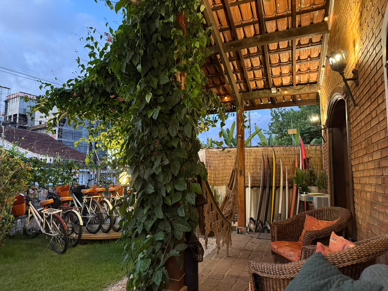 Varanda da Golden Garden House com rede, pranchas de surf e bicicletas no jardim dourado