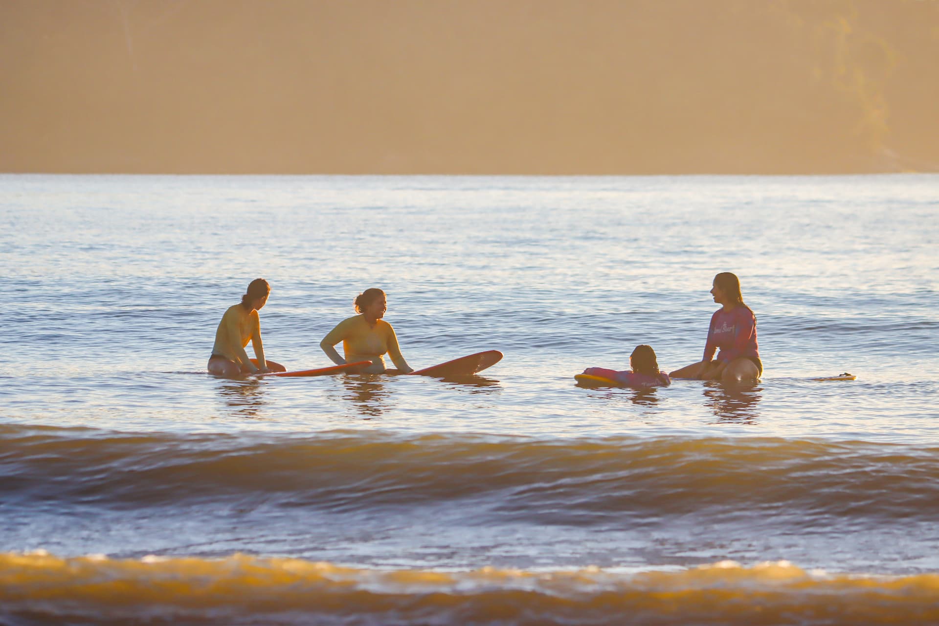 Grupo no mar ao amanhecer com as pranchas, esperando as ondas