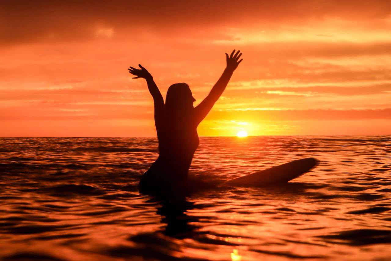 Silhueta de surfista comemorando no mar ao pôr do sol em Ubatuba